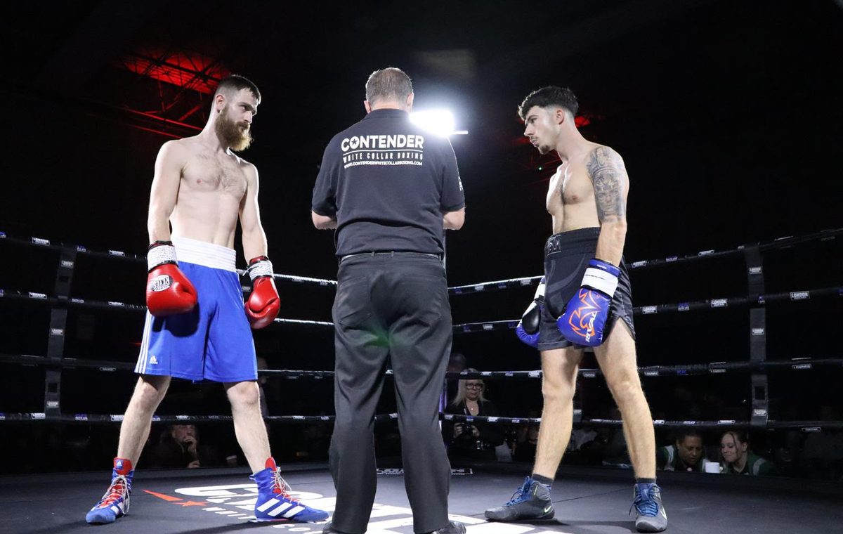 Two Contender fighters face off in the ring as the referee in a Contender White Collar Boxing shirt gives final instructions